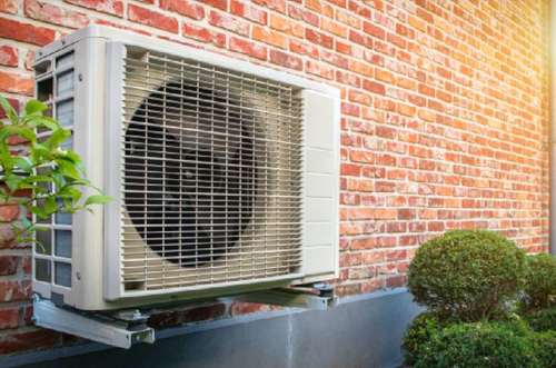 Buitenunit van een airco of warmtepomp gemonteerd tegen een bakstenen gevel
