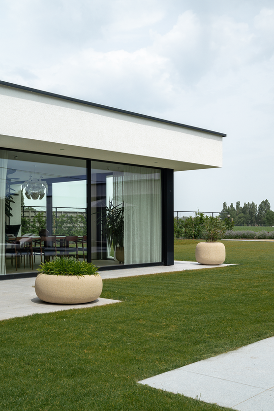 Detail van een moderne witte villa met minimalistische architectuur, slanke dakrand en grote raampartijen.
