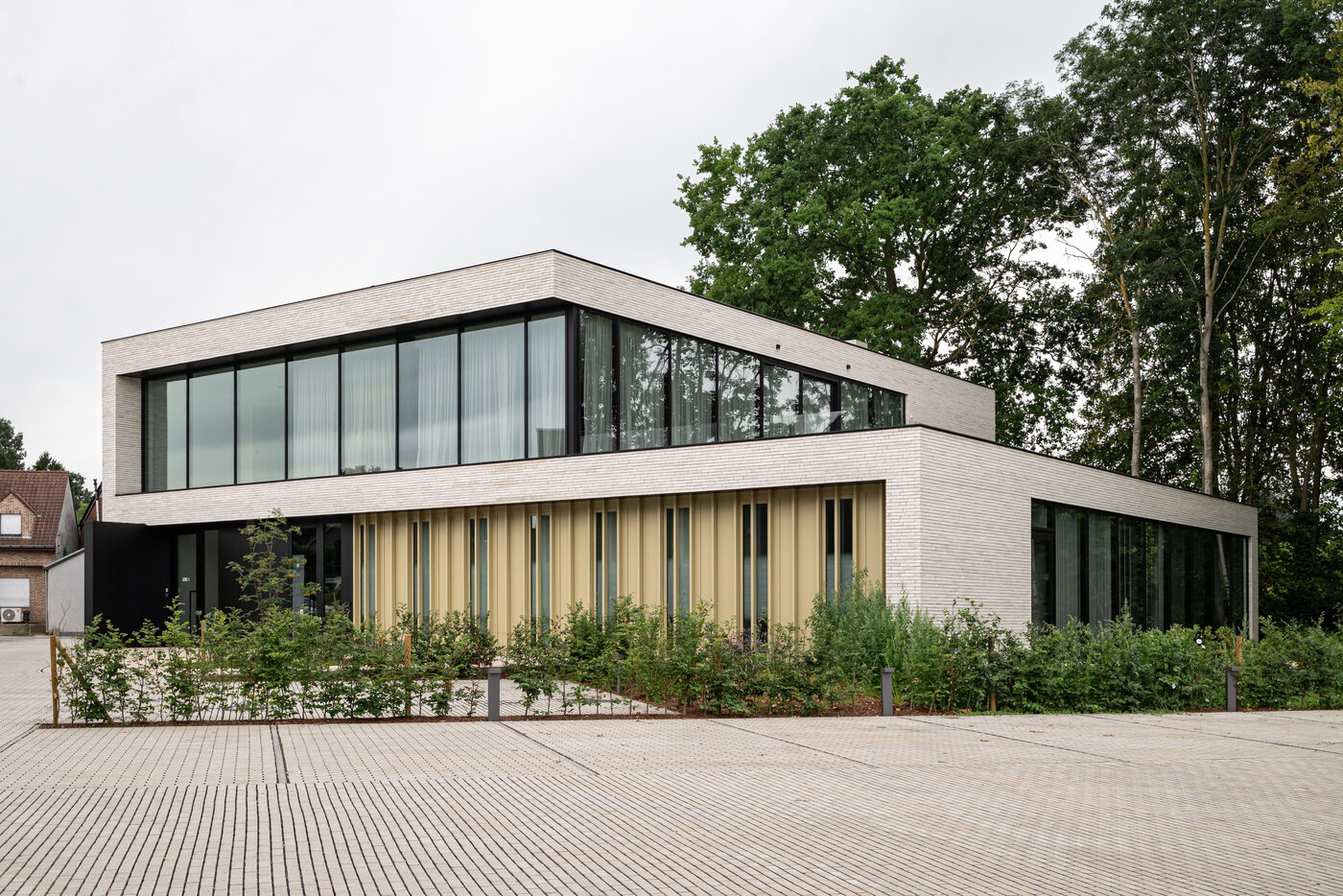 Modern kantoorgebouw met lichte gevelsteen, grote glaspartijen en verticale aluminium lamellen, ontworpen door GC Architecten.