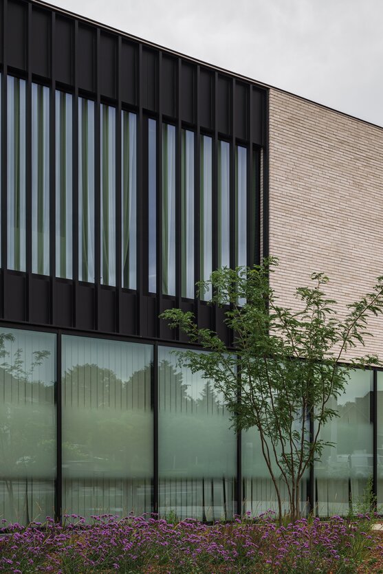 Detail van de moderne kantoorarchitectuur met verticale aluminium gevelstructuur en lichte gevelsteen.